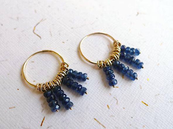 זוג עגילי חישוק עם תליוני שרשראות ספירים ואלמנטים של חישוקי צמה ביניהם. עגילי סטייטמנט בוהו מעוטרים באבני חן חרוזי ספיר כחול זהב אמיתי 14 קרט עיצוב מלכותי