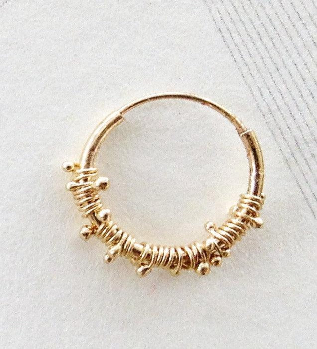 A single 14K solid gold hoop earring with coiled wire details and small ball embellishments.
