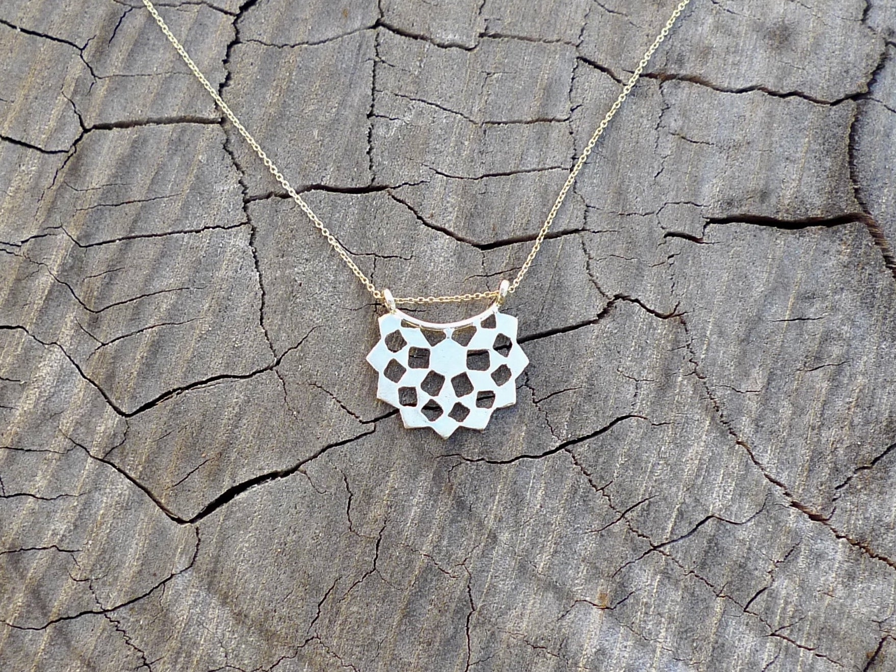 Necklace with a geometric pendant on a textured wooden surface