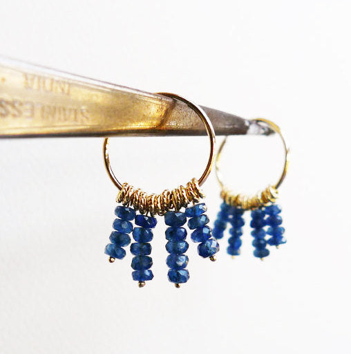 dangle blue and gold unique hoops. 14 karat gold hoop earrings with 4 strings of blue sapphire gemstone beads and braided tiny loop elements. recycled gold fair trade sapphires. oriental boho style handmade gold earrings. evil eye protection color.