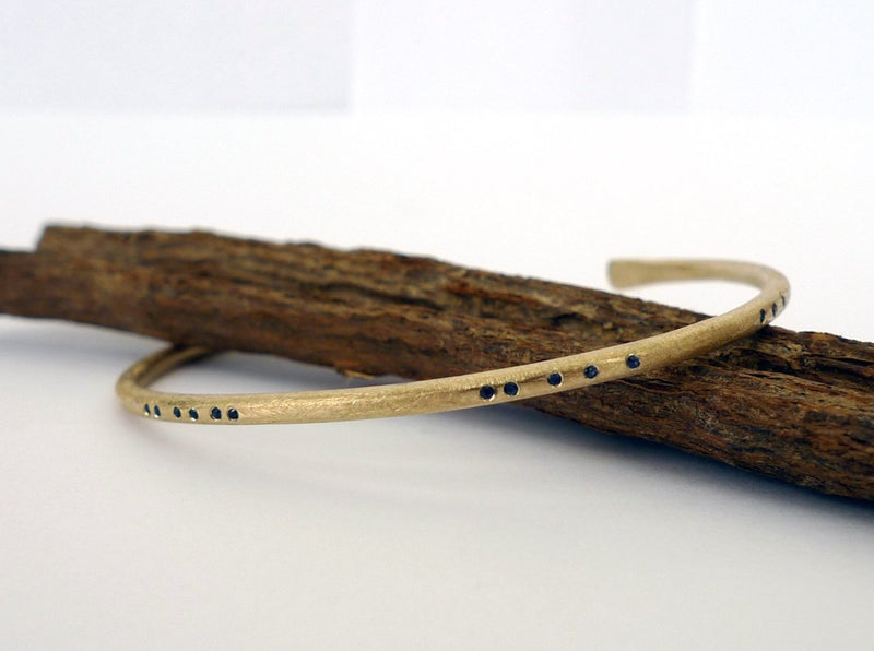 alternative bangle. 14k recycled gold handmade rustic earthy style bracelet. cuff set with blue sapphire. morse code arrangement gold jewelry. fair trade sapphires. 
