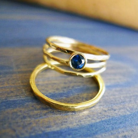 טבעת ליפופים יחודית חיבוק רצועות דקות מרוקעות זהב 14 קרט עוטפת בשיבוץ אסימטרי אבן ספיר כחולה תכשיטי מעצבים